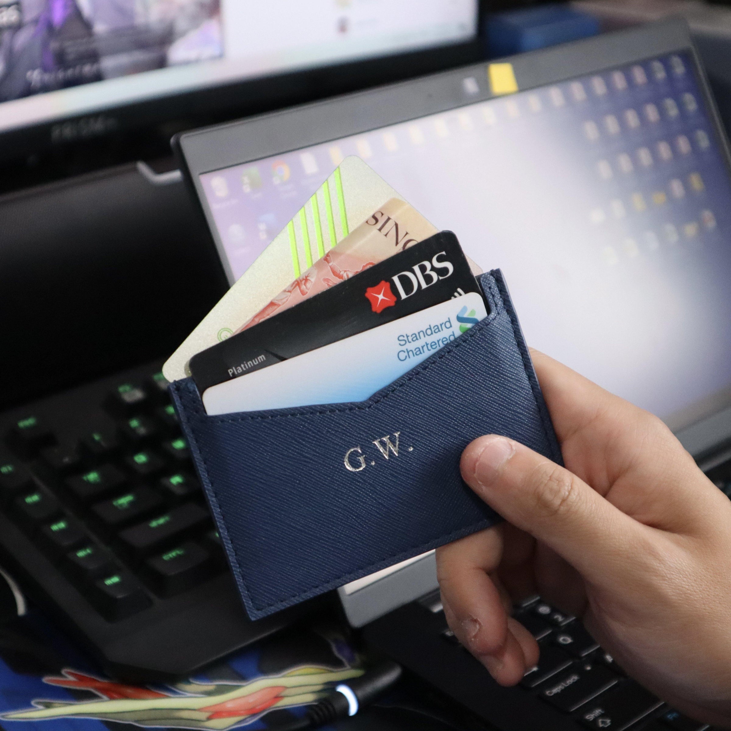 Hand holding a Navy personalised leather cardholder filled with credit cards. 